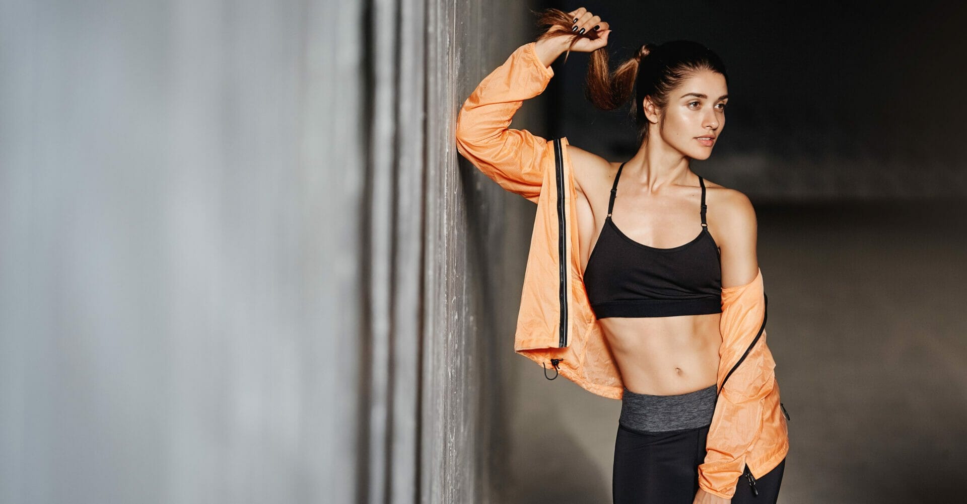 A woman in workout clothes leaning against a wall.