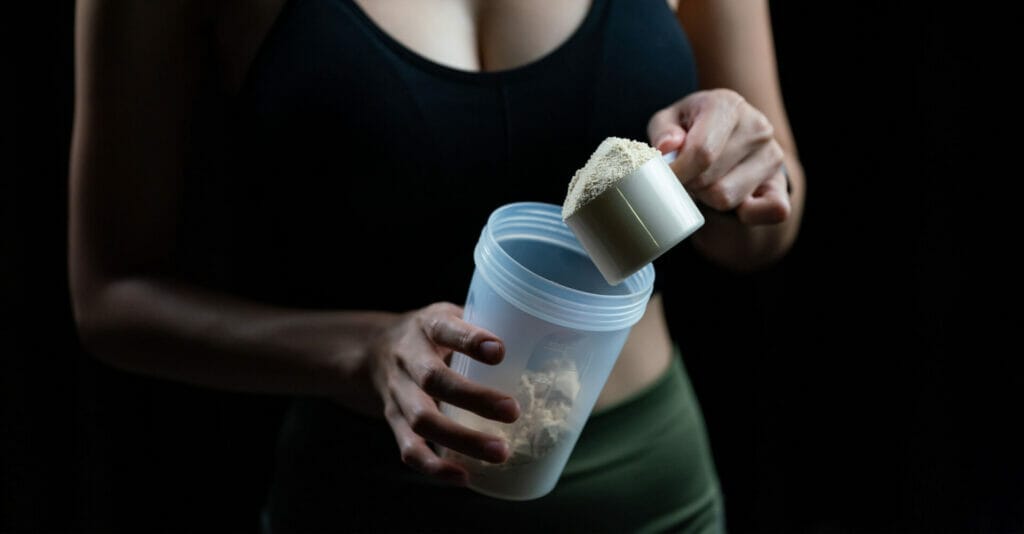 A woman holding a measuring cup with a powder in it.
